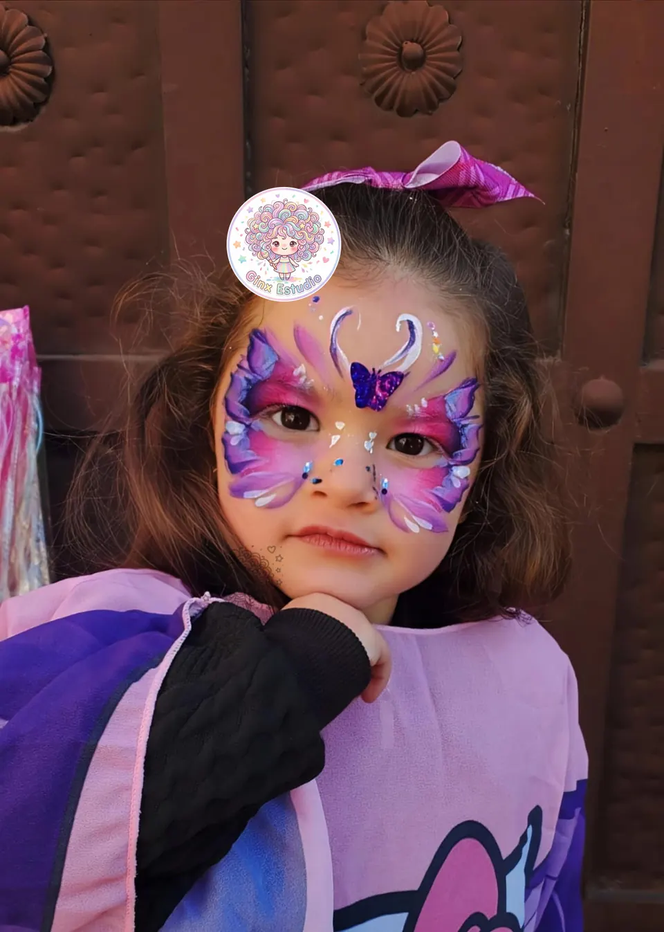 Niña con antifaz de mariposa morada pintado