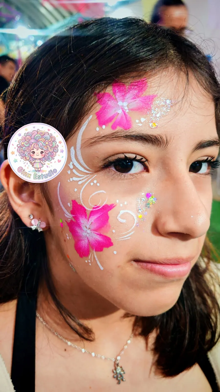 Flores rosas pintadas en la mejilla con brillos