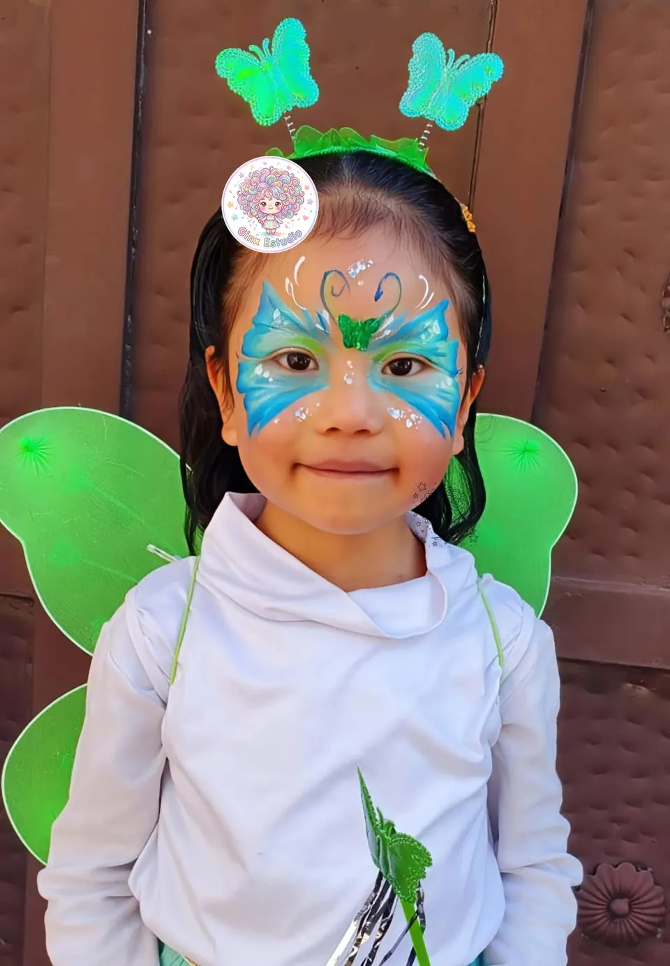 Niña con mariposa azul pintada y alas verdes