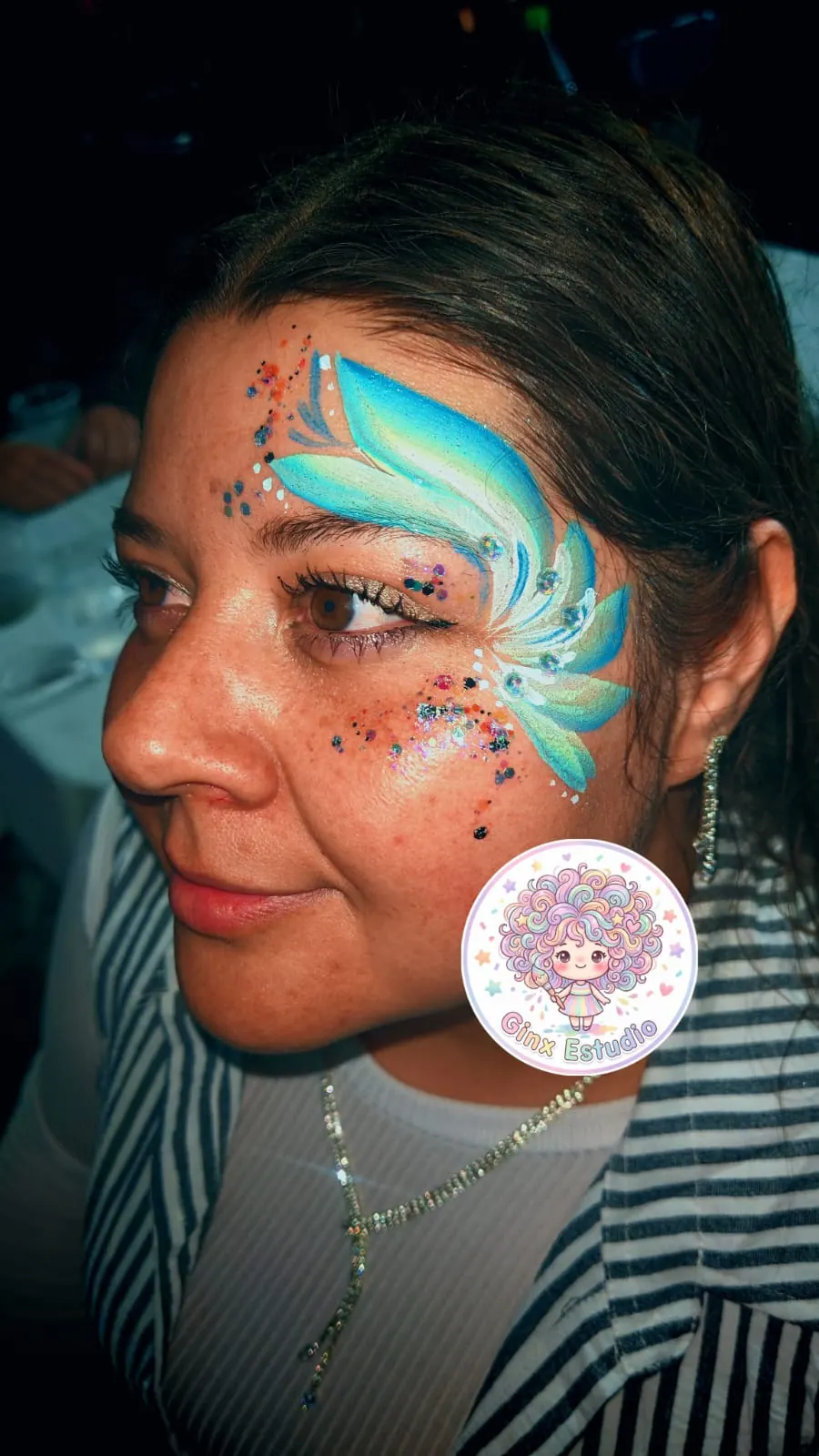 Ola turquesa pintada en la sien con gemas y brillos
