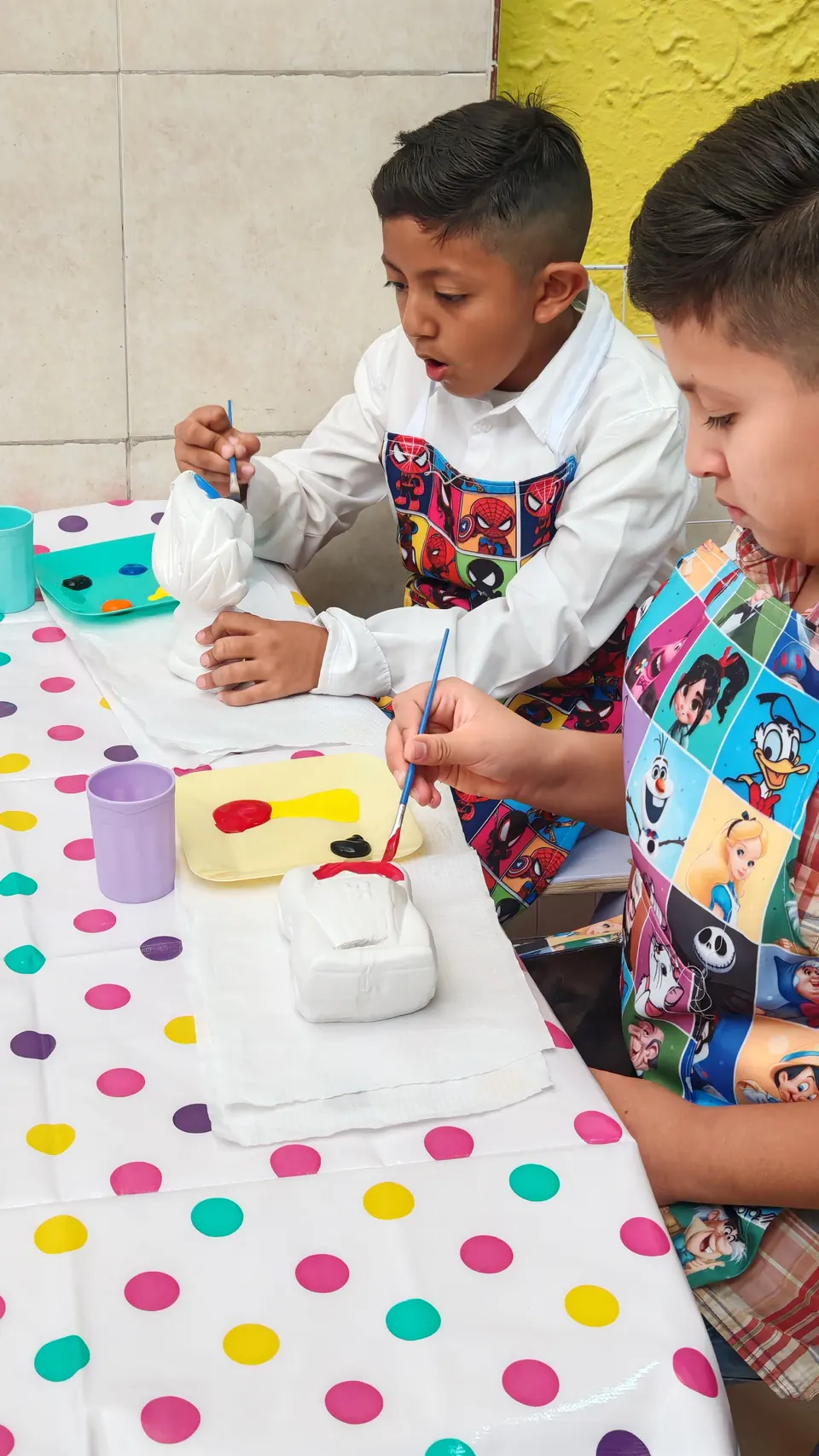 Dos niños pintando sus yesitos en el taller